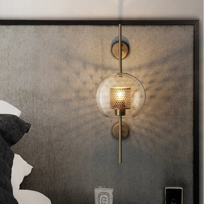 Modern bedroom with wall sconce, books, and a candle on a nightstand.