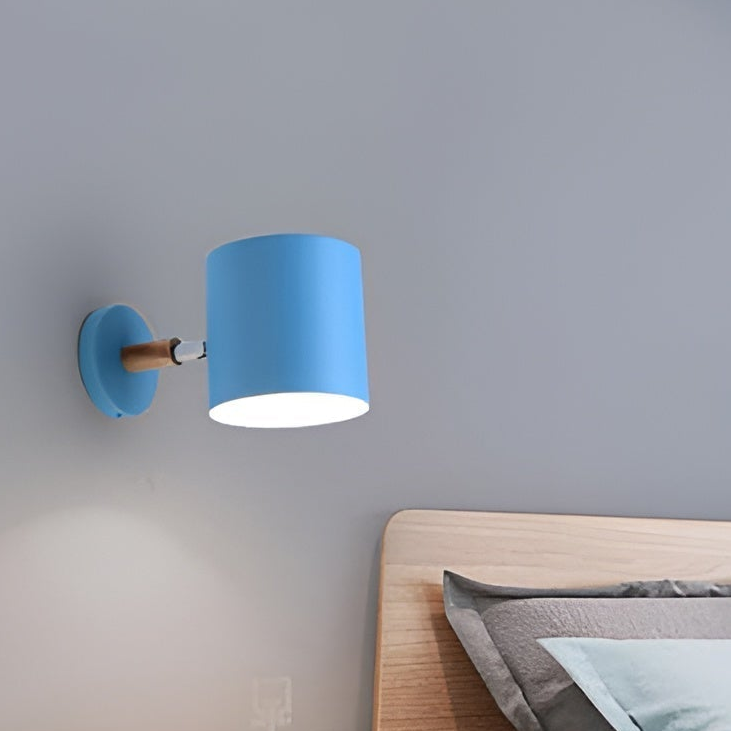 Blue wall lamp above a bed with wooden nightstand and decor items.